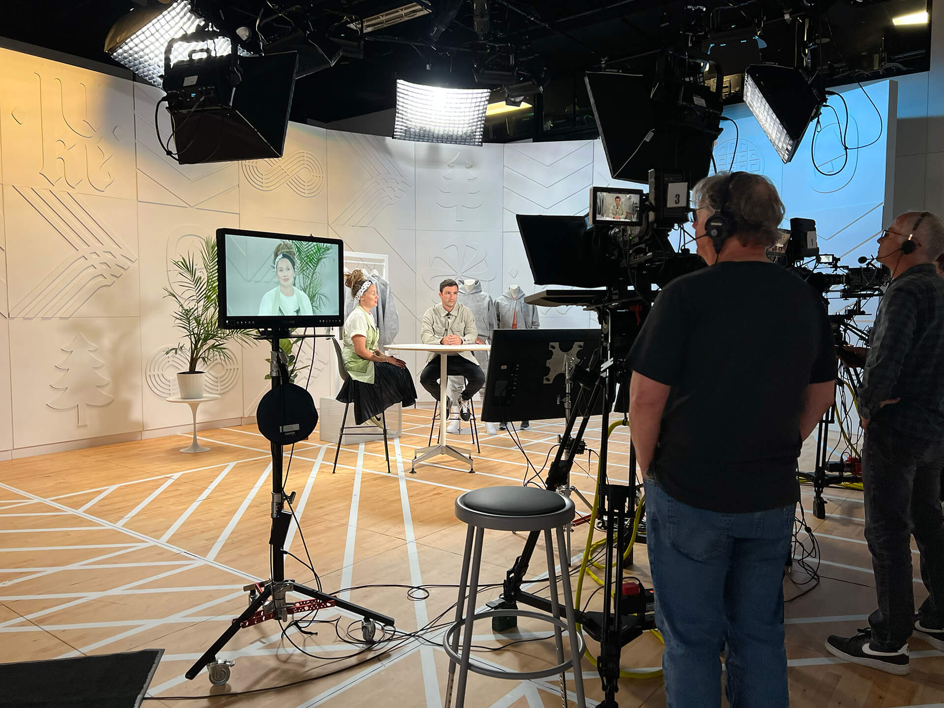 Two hosts on the webinar set in front of the embossed Nike Forward icon wall