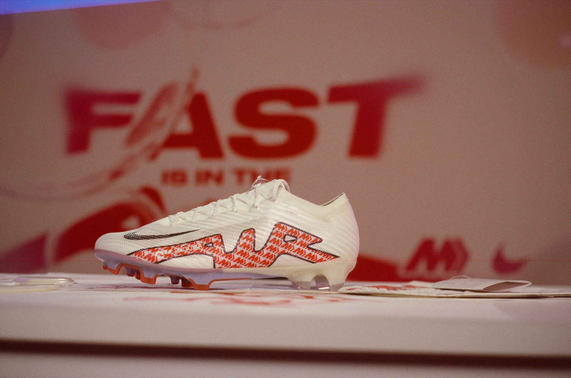 Air Zoom Mercurial boot staged on the desk against the Fast Is in the Air wall